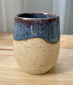 a blue and brown cup sitting on top of a wooden table