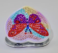 a colorful butterfly shaped compact purse with pearls on the front and sides, sitting on a white surface