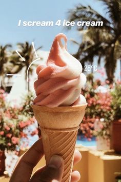 a hand holding an ice cream cone in front of a palm tree and blue sky