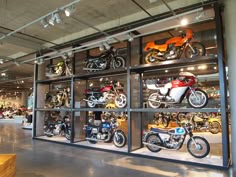 several motorcycles are on display in a glass case