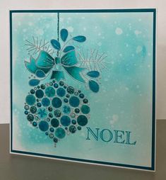 a card with a blue and green christmas ornament hanging from it's side