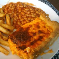 a white plate topped with food next to french fries and baked beans on top of it