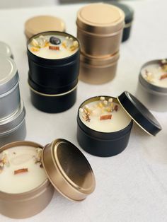 several small tins filled with food sitting on a white tablecloth covered table next to each other