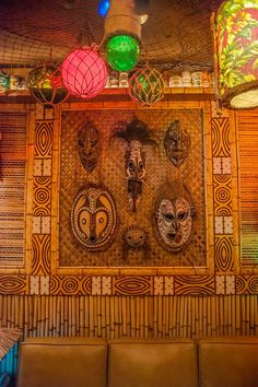 an artisticly decorated wall in a restaurant with leather couches and lamps hanging from the ceiling