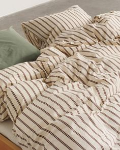 an unmade bed with striped sheets and pillows