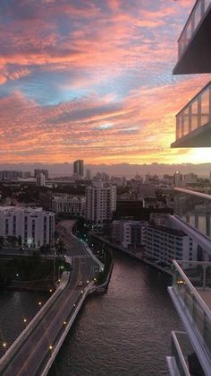 the sun is setting over an urban area with tall buildings and river running through it