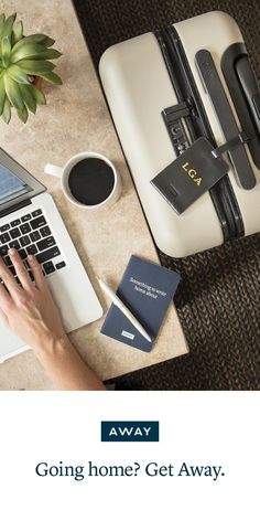 there is a woman typing on her laptop next to some luggage and other items that are sitting on the table