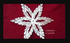 a white paper snowflake sitting on top of a red blanket