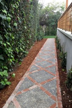 a walkway between two buildings with plants on either side