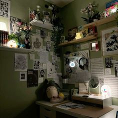 a desk with many pictures on the wall above it and a lamp in front of it