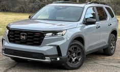 a grey honda passport parked in front of a fence