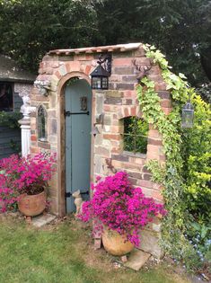 an outdoor garden with potted plants and flowers in front of a stone building that has a blue door