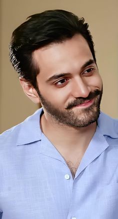 a man with a goatee and beard smiling at the camera while wearing a blue shirt