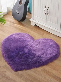 a purple heart shaped rug in the middle of a wooden floor next to a guitar