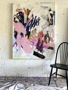 an abstract painting hangs on the wall next to a black chair in front of it