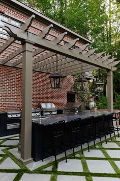 an outdoor kitchen and dining area with green grass on the floor, surrounded by brick walls