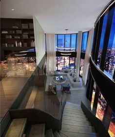 a living room filled with lots of furniture and tall windows next to a stairway leading up to the top floor