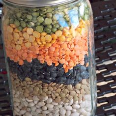 a jar filled with lots of different types of beans and veggies on top of a table