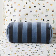 a blue and black striped pillow sitting on top of a bed next to a wall