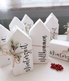 small white wooden houses tied with twine and decorated with holly berries, sitting on a table