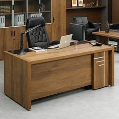 an office desk with a laptop on it in front of a bookcase and chairs