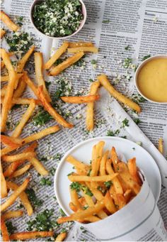 some french fries are on a white plate and next to a bowl of dipping sauce