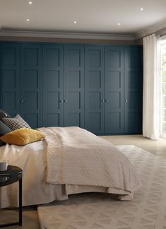 a bedroom with blue cabinets and a white bed