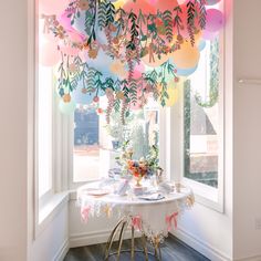 a dining room table with balloons hanging from it's ceiling and plates on the table