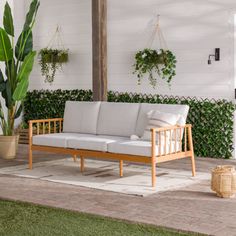 a white couch sitting on top of a patio next to a potted green plant