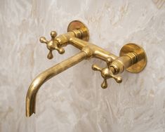 an antique brass faucet on a marble wall