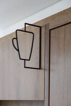 a close up of a kitchen cabinet with a cup on the door and a handle