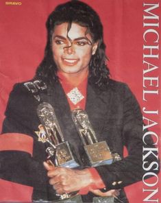 michael jackson holding two trophies in front of a red background with the words michael jackson on it