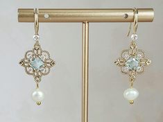 **All orders come with tracked shipping** 18k champagne gold plated brass Aquamarine art deco style crystal earrings. These gorgeous earrings have a diamond shape aquamarine stone, surrounded by gold filigree work and small clear rhinestones at the corners followed by round white natural freshwater pearls. All jewelry comes in a gift box. If you would like gift wrapping, please enter this request in the personalization section. Gift wrapping is free of charge. Ready to ship in 1-3 business days Edwardian Earrings, Bridgerton Jewelry, Light Blue Art, Blue Art Deco, Deco Earrings, Aquamarine Earrings, Bride Earrings, Art Deco Necklace, Aquamarine Stone