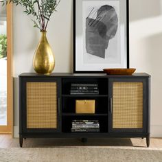 a black and gold sideboard in a living room with pictures on the wall behind it