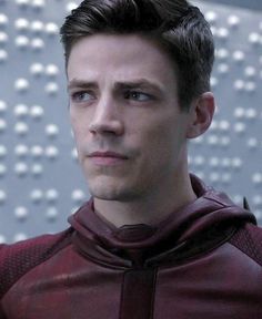 the young man is dressed in a maroon outfit and looking at the camera with serious eyes