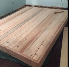 a bed frame made out of wooden planks in a room with hard wood flooring