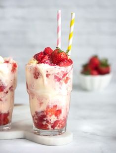 two glasses filled with ice cream and strawberries on top of a white countertop