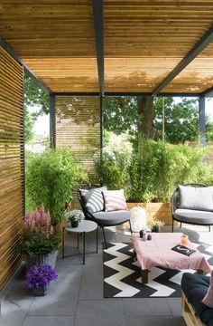 an outdoor living area with black and white checkered rugs on the floor, two couches in front of a wooden pergol