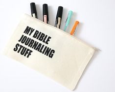 four pens sitting in a pouch with the words my bible journaling stuff on it