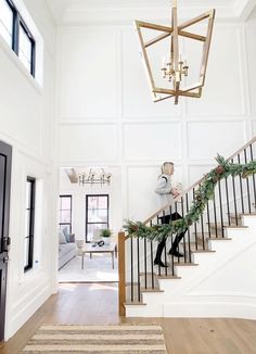 a person walking down the stairs in a house with christmas decorations on it's handrails