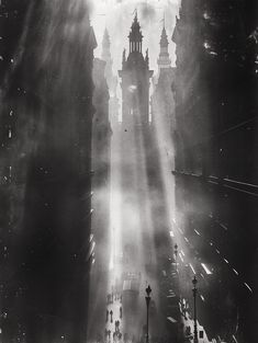 an old black and white photo of the sun shining down on a city street with tall buildings