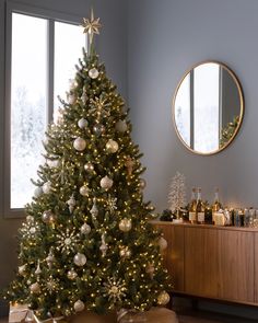 a decorated christmas tree in a living room with presents on the floor and a round mirror