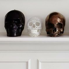 three skulls sitting on top of a white shelf