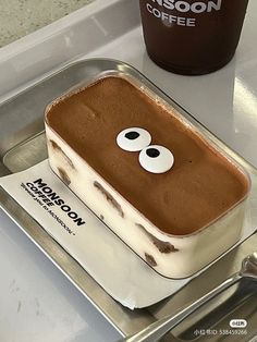 an ice cream dessert with eyes and googly eyes on it next to a cup of coffee