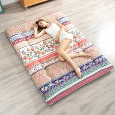 a woman laying on top of a multicolored bed in the middle of a room