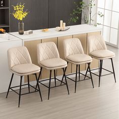 four stools are lined up in front of a counter with flowers and candles on it