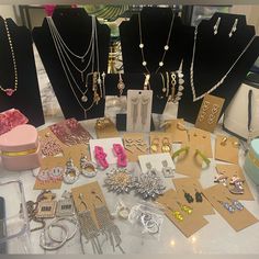 a table topped with lots of different types of necklaces and earrings on top of cards