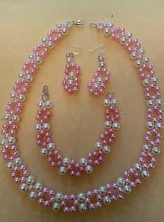 a pink and white beaded necklace and earring set with matching earrings on display