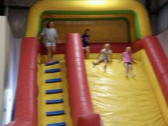 three children are playing on an inflatable slide