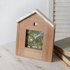 a small wooden house frame sitting on top of a table next to a stack of books